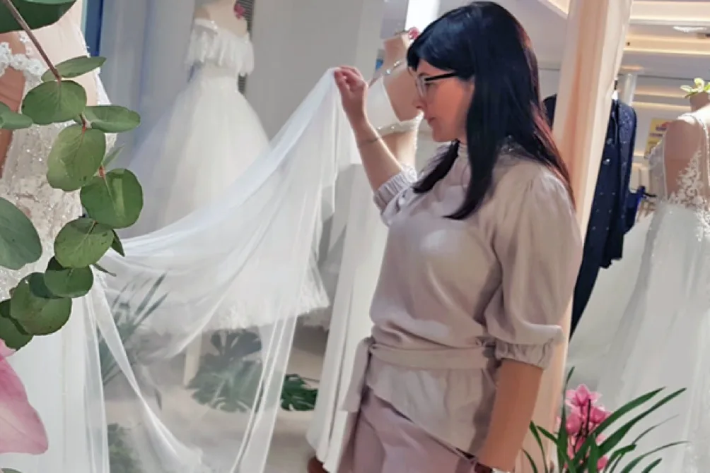 Antonella al lavoro con un abito da sposa in atelier